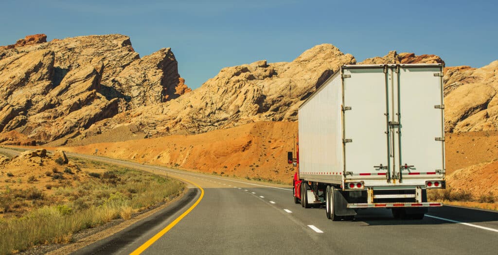 Semi truck driving on an open desert road